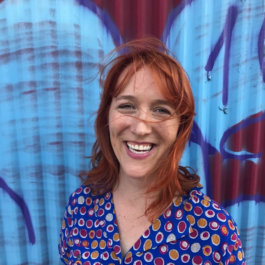 Kim Purcell smiling in front of a colorful mural